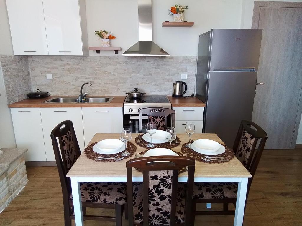 a kitchen with a table with chairs and a refrigerator at IL TRAMONTO APARTMENT 1 in Kanali