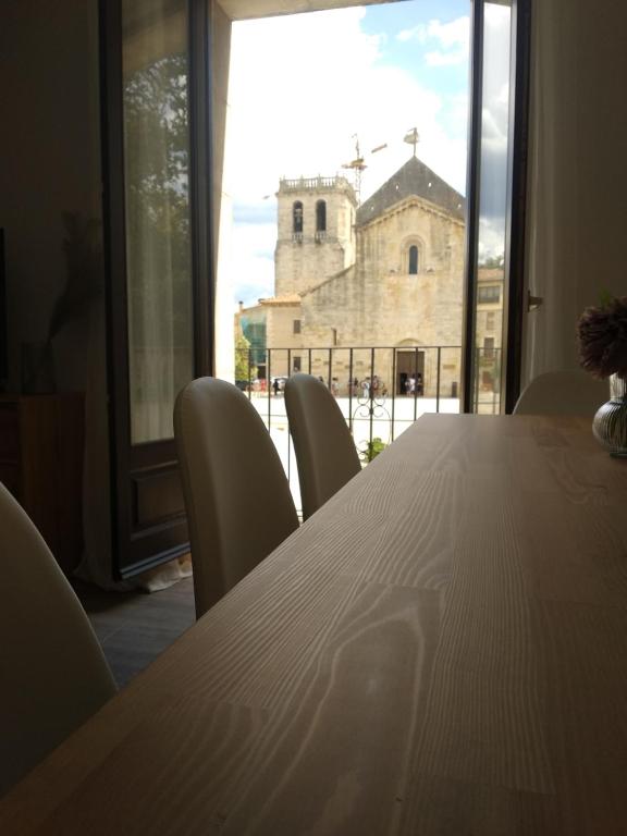 mesa con sillas y ventana grande con iglesia. en Can Silvestre, en Besalú