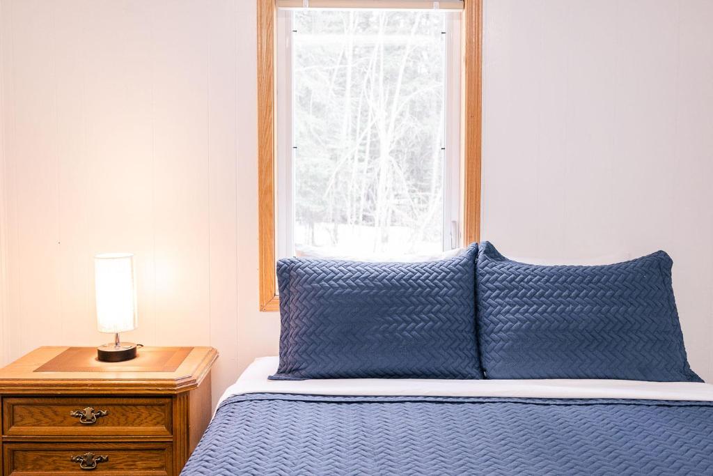 a bed with a blue comforter and a window at Delta Lodge in Delta Junction