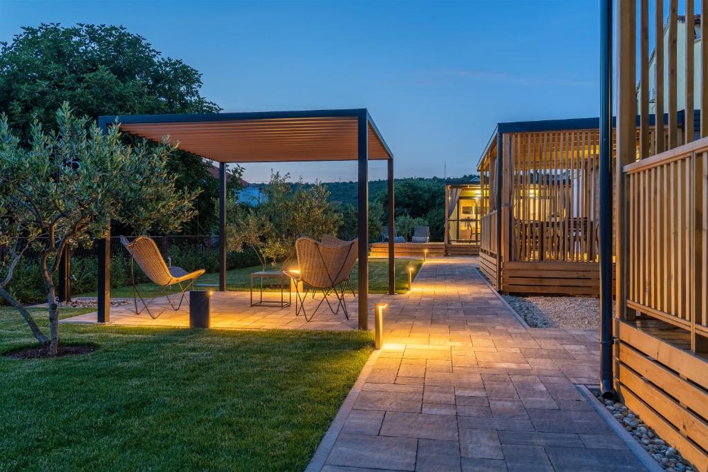 蘇科尚的住宿－Giardino Sukošan - new mobile houses in olive garden, EV plug-in station，一个带椅子的庭院和一个带灯的凉亭