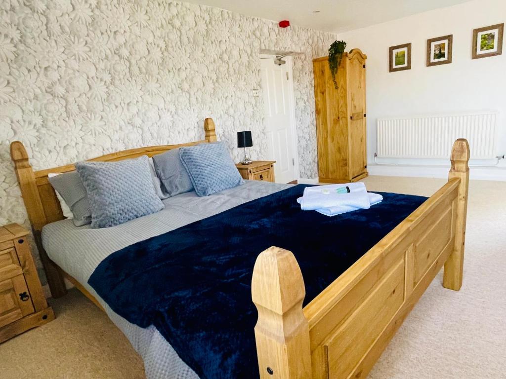 a bedroom with a large wooden bed with blue sheets at The Maltsters Country Inn in Badby