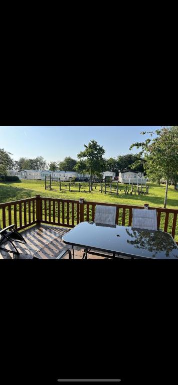 a table and chairs on a deck with a view of a park at The Luxury break Sleeps 6 at Kingfisher Court South facing in Tattershall