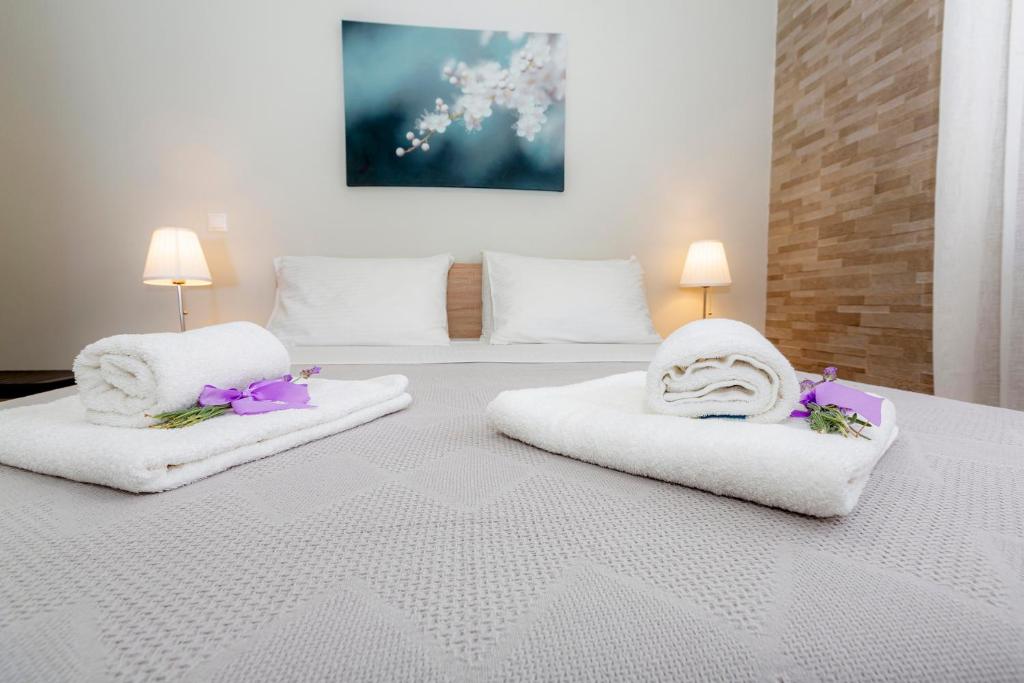 a bedroom with two beds with white towels and purple flowers at sofia's apart 4u (114) in Glyfada