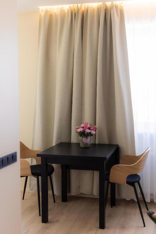 a black table with flowers on it in front of a window at Windy City apartments in Liepāja