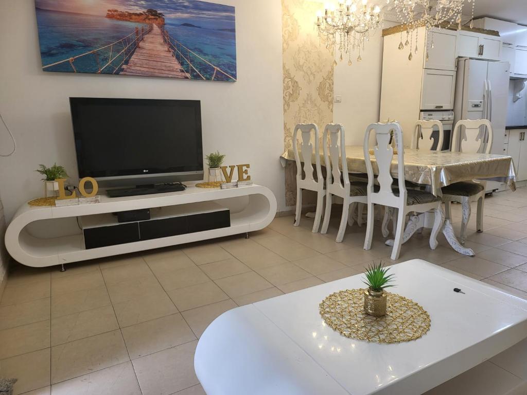 a living room with a tv and a table with chairs at תהילה בכנרת in Tiberias