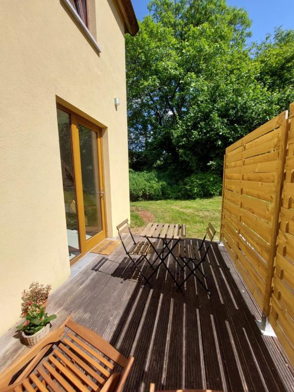 een houten terras met 2 stoelen en een hek bij Le Gîte du Herdal in Profondeville