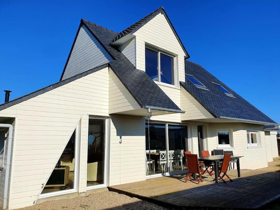 une maison blanche avec une table et des chaises sur une terrasse dans l'établissement Maison spacieuse et lumineuse à 2mns des plages, à Locquirec