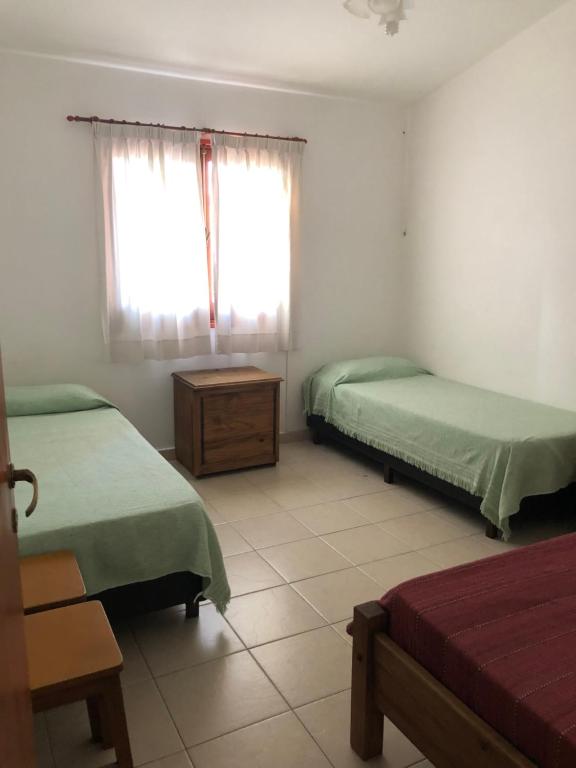 a bedroom with two beds and a table and a window at Casa La Quinta in Villa Carlos Paz