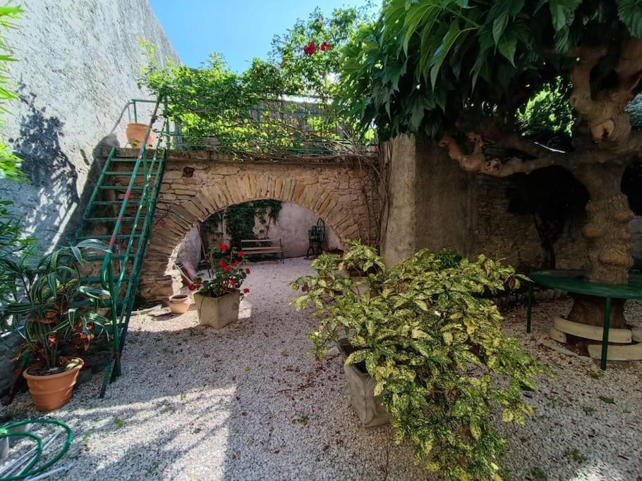 une arche en pierre avec des plantes et une table verte dans l'établissement Maison de village 8 couchages, à La Livinière