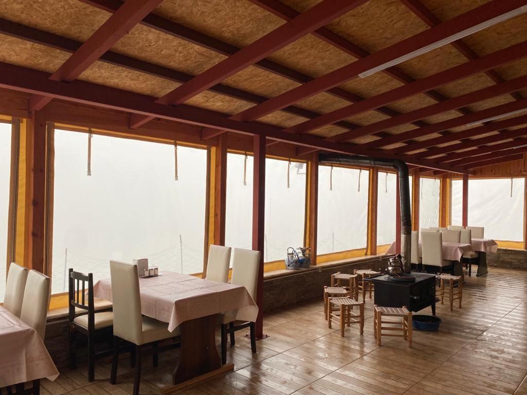 a dining room with tables and chairs and windows at Avusor mola cafe pansiyon in Çamlıhemşin