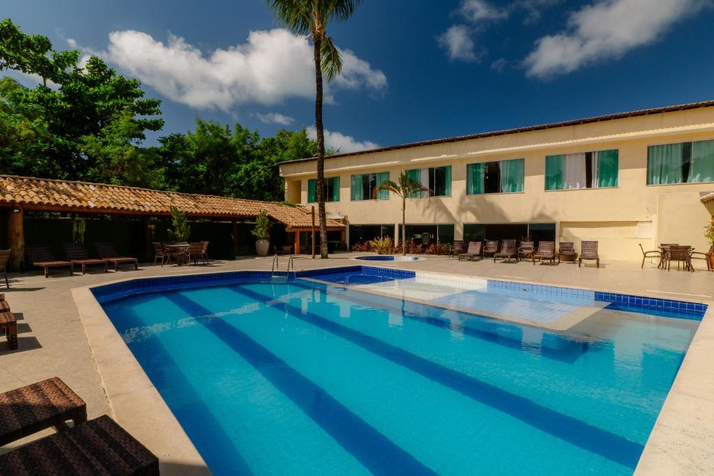 a large swimming pool in front of a building at Miola Hotel in Porto Seguro