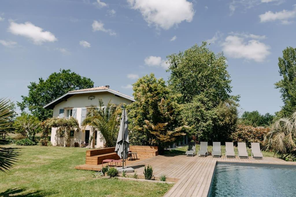 une arrière-cour avec une piscine, des chaises et une maison dans l'établissement Maison de l'Ouest, à Biaudos