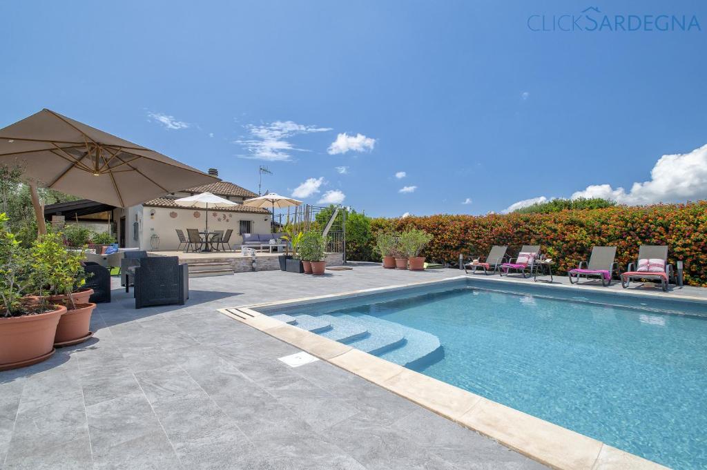 - une piscine avec des chaises et un parasol dans l'établissement ClickSardegna Villa Lavinia con piscina e accesso alla laguna Calich, à Casa Linari