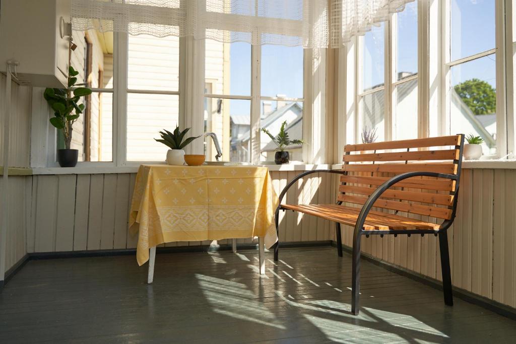 a bench and a table in a room with windows at Amalie Apartment in Haapsalu