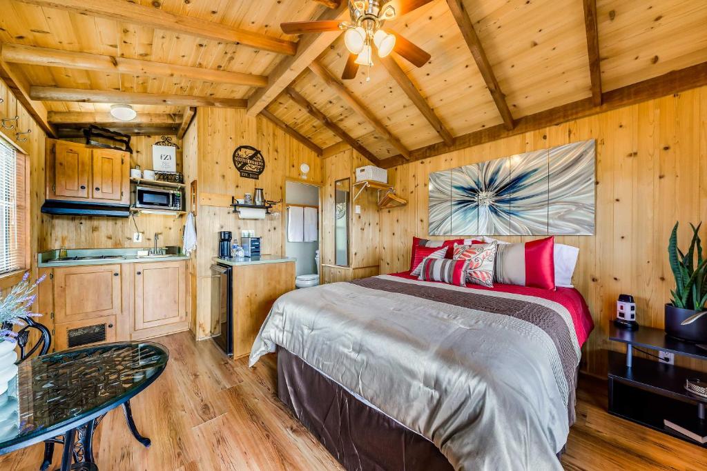 a bedroom with a large bed in a room with wooden walls at Tiny Home with Covered Porch in Cloudcroft Area! in Mayhill