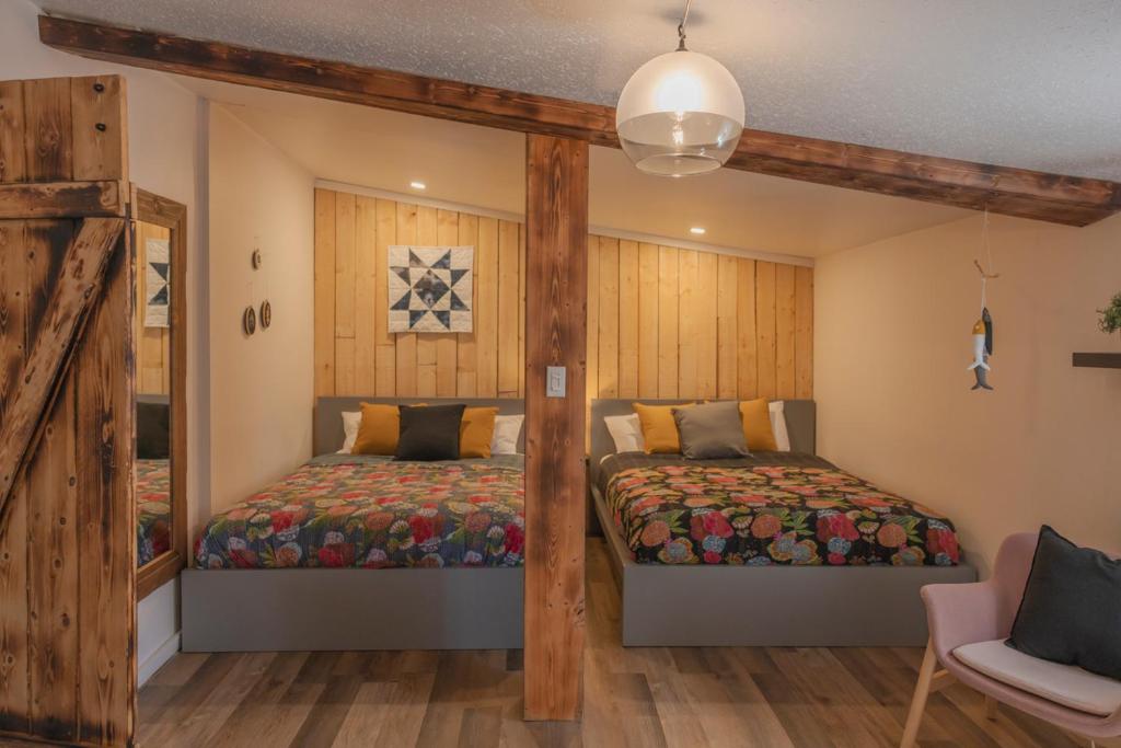 2 camas en una habitación con paredes de madera en Jaune Hôtel-Boutique, en Saint-Gédéon