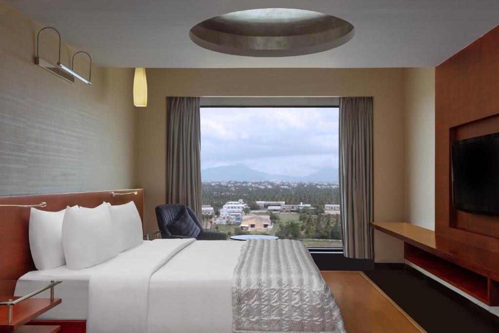 a hotel room with a bed and a large window at Le Meridien Coimbatore in Coimbatore