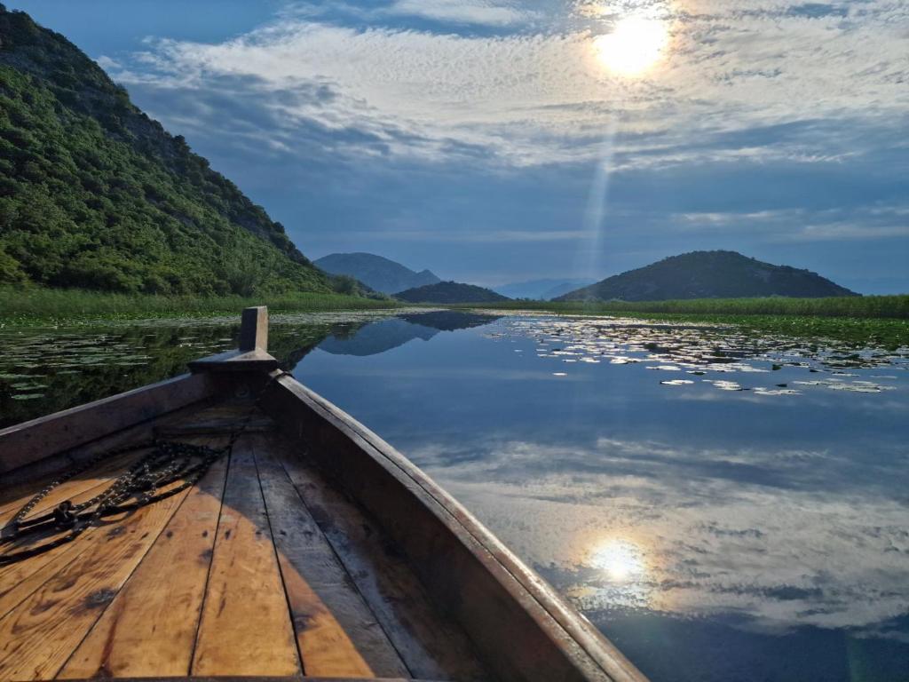 een houten boot op een rivier met bergen op de achtergrond bij JOCKER in Virpazar