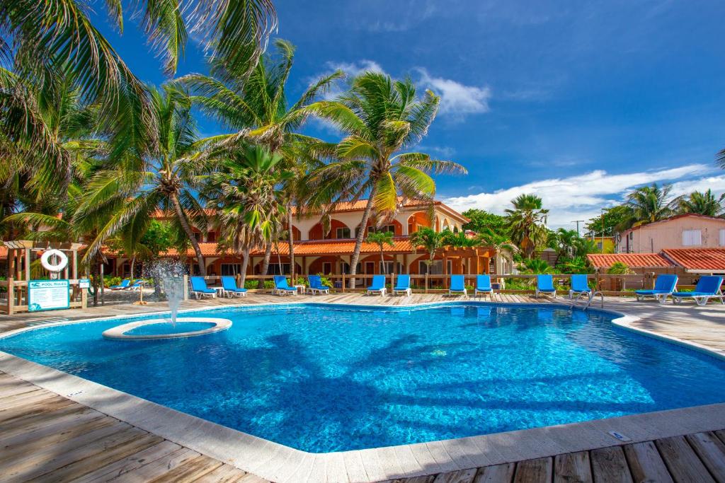 una piscina con palmeras y sillas azules en SunBreeze Hotel, en San Pedro