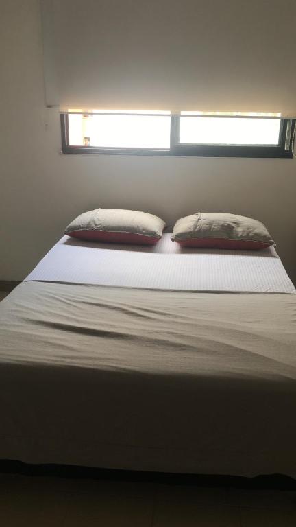 カリにあるMy placeの枕が2つと窓のある白いベッド