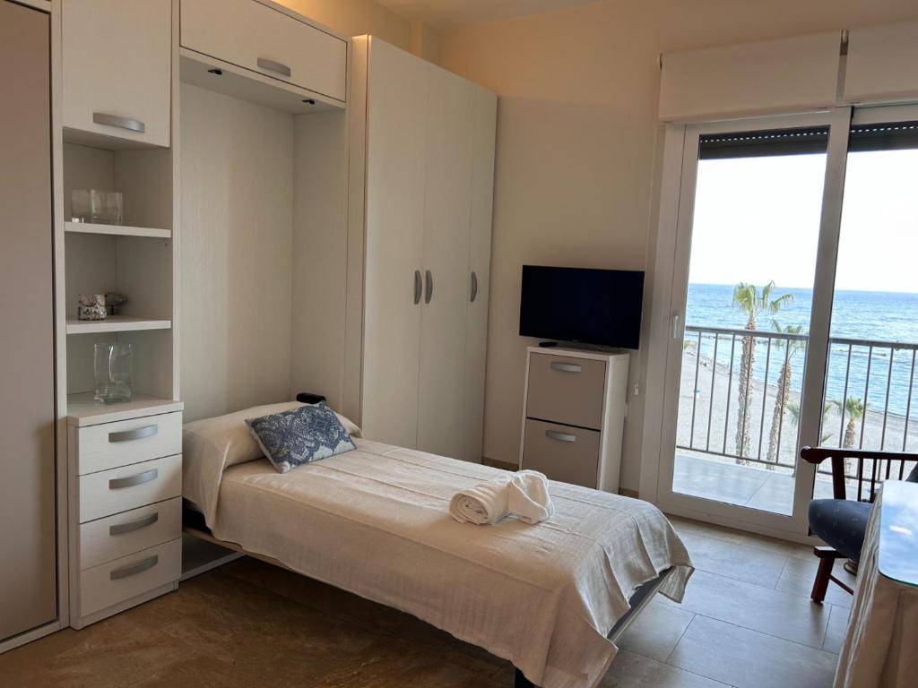 1 dormitorio con 1 cama, TV y ventana en ESTUDIO PORTAMAR, en Almuñécar