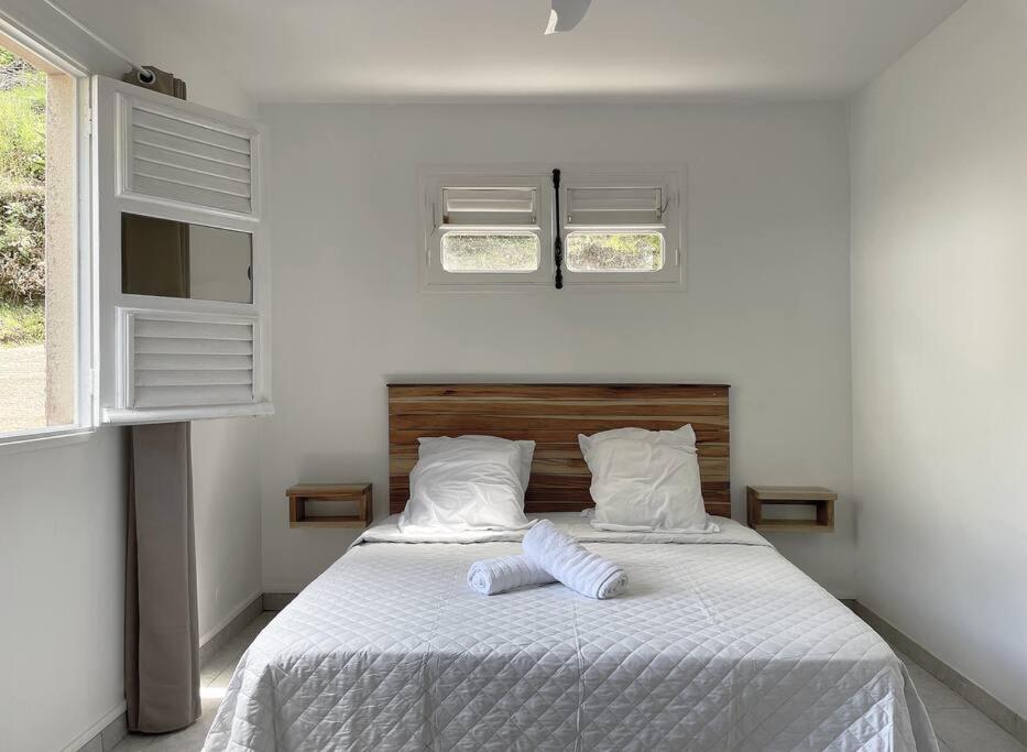 a bedroom with a bed with white sheets and two pillows at Spacieux appartement à La Villa Montagne in Le Carbet