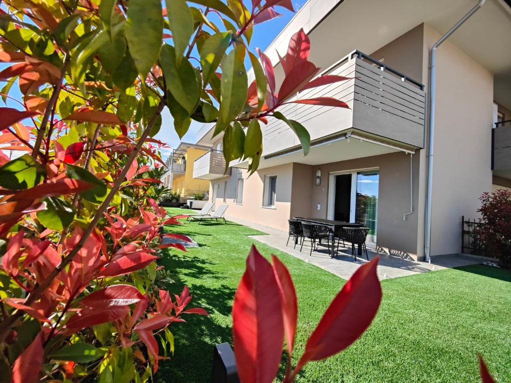 einen Hinterhof mit grünem Gras und roten Pflanzen in der Unterkunft San Giorgio Design Home in Colà di Lazise