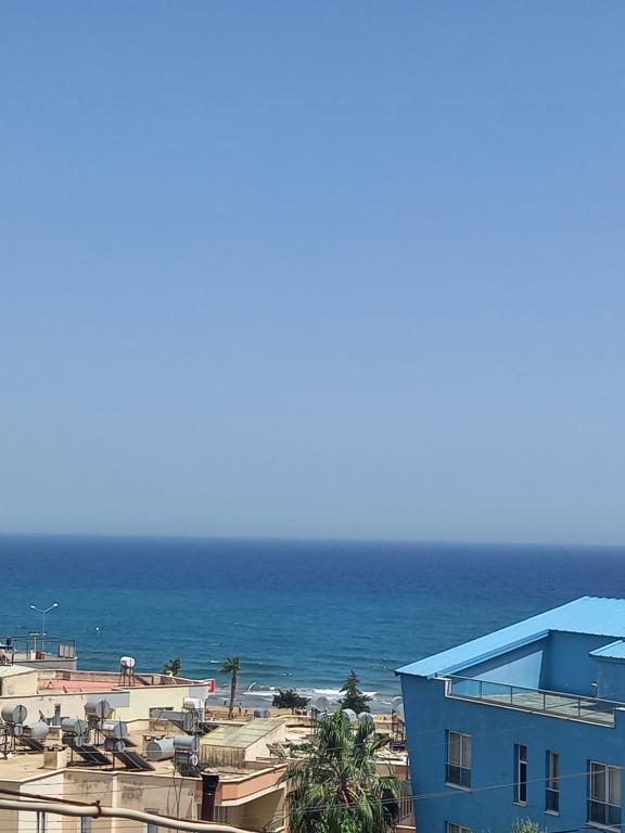 Blick auf einen Strand mit einem blauen Gebäude und das Meer in der Unterkunft Yasemin Yazlık Pansiyon in Erdemli