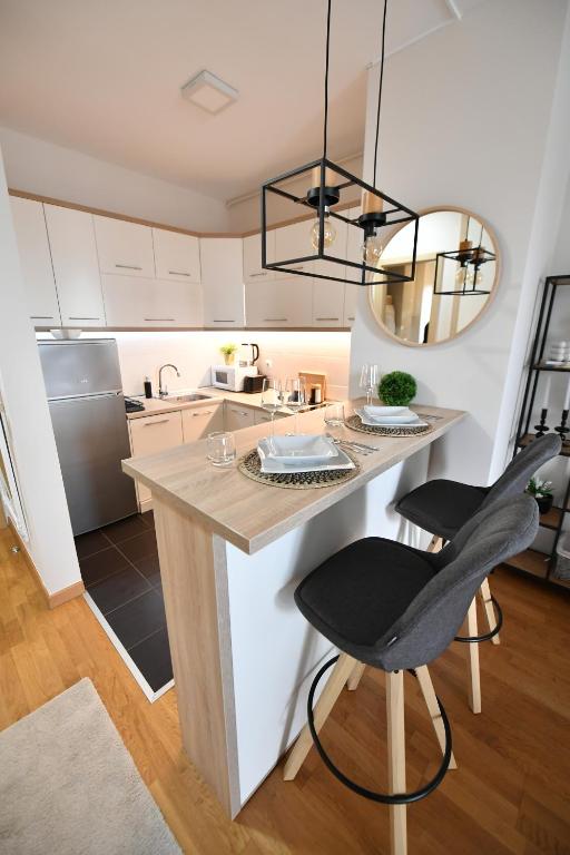 a kitchen with a large island with two chairs at Apartman SUN in Inđija
