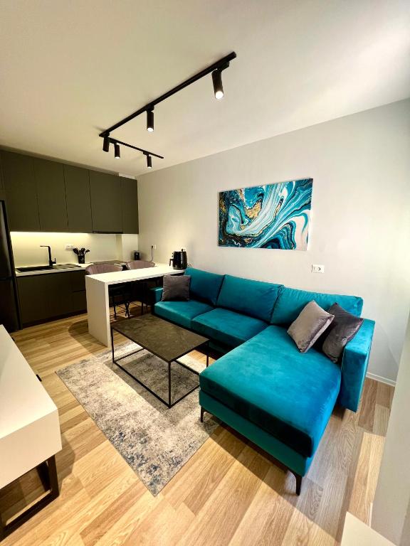 a living room with a blue couch and a kitchen at Center of Tirana - Apartment in Tirana