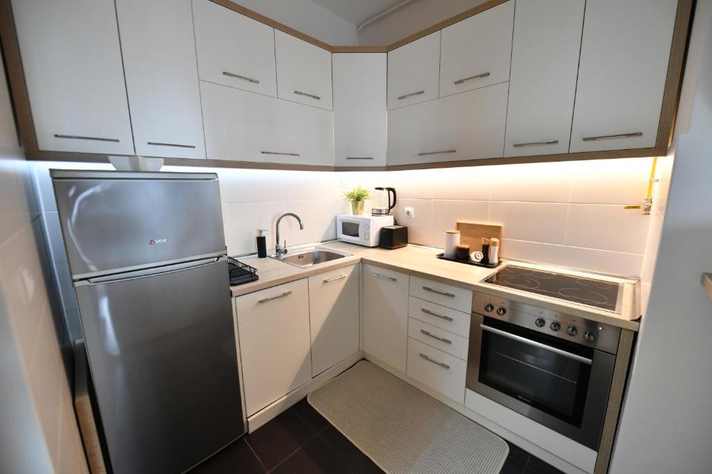 a kitchen with white cabinets and a stainless steel refrigerator at Apartman SUN in Inđija