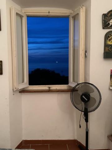 a room with a window with a fan in front of it at Maison Des Amis in Capraia