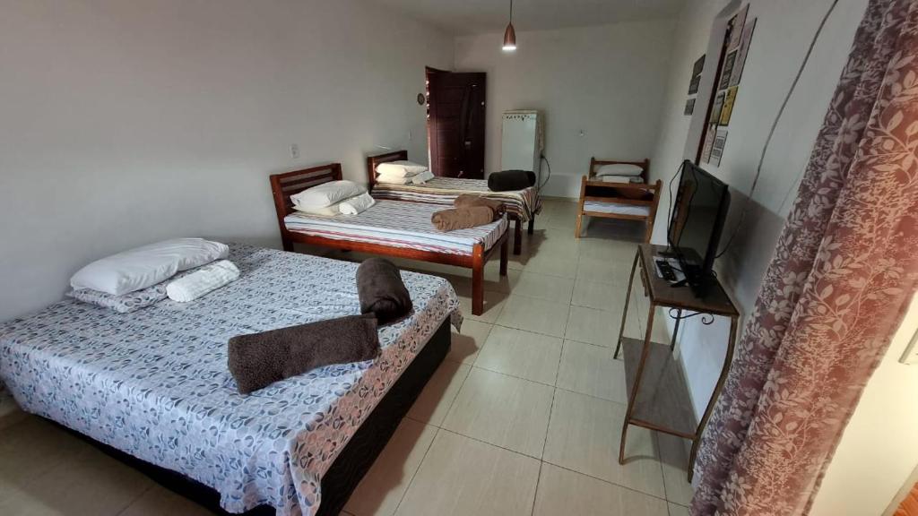 a room with three beds and a television at SUITE - CIDADE das CACHOEIRAS in Santa Rita de Jacutinga