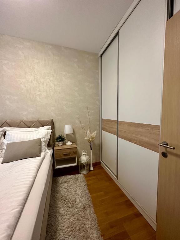 a bedroom with a bed and a sliding glass door at Apartman SUN in Inđija