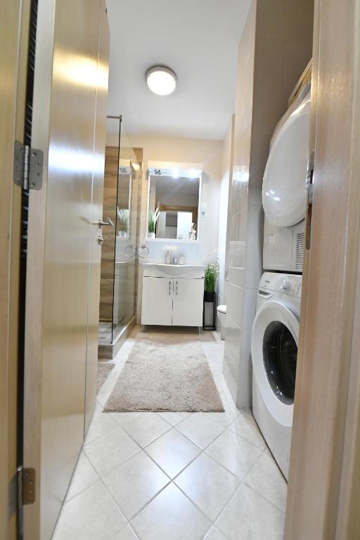 a bathroom with a washing machine and a sink at Apartman SUN in Inđija