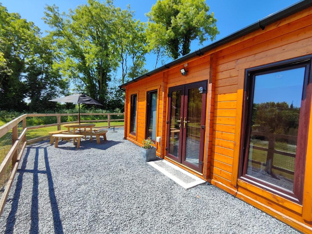 uma cabina de madeira com uma mesa de piquenique e um guarda-chuva em Desart School Garden Chalet em Kilkenny