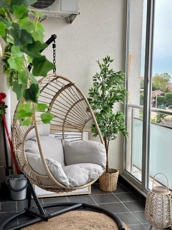 a rattan swing sitting on a balcony with plants at Apartman SUN in Inđija