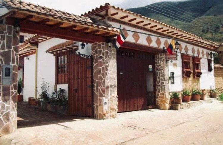 un edificio con 2 puertas de madera y una montaña en Hotel Villa Cristina, en Villa de Leyva