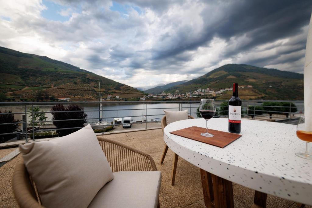 una mesa con una botella de vino y una copa en Hotel Folgosa Douro en Armamar