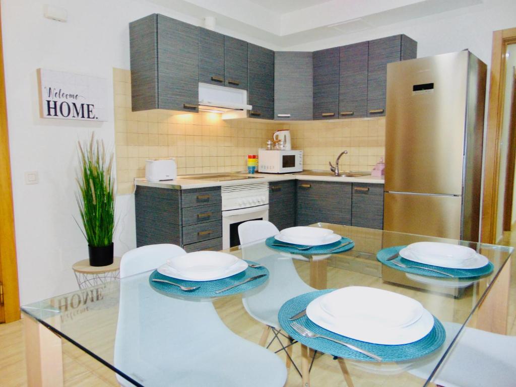 a kitchen with a glass table with chairs and a refrigerator at Casa Paty Fuerteventura in Puerto del Rosario