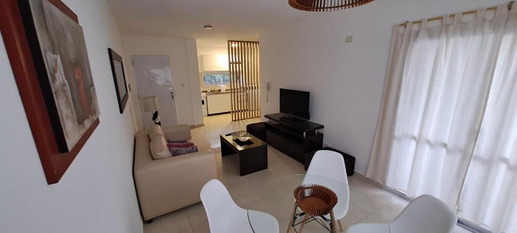 una sala de estar con muebles blancos y sillas blancas. en Departamento Temporario - Barrio San Isidro (Malibu) en Villa Allende