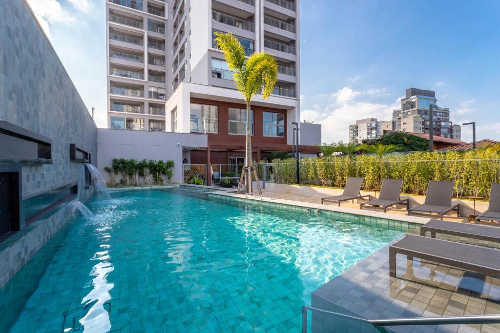 a swimming pool with chairs and a building at Charlie For You Vila Mariana in Sao Paulo