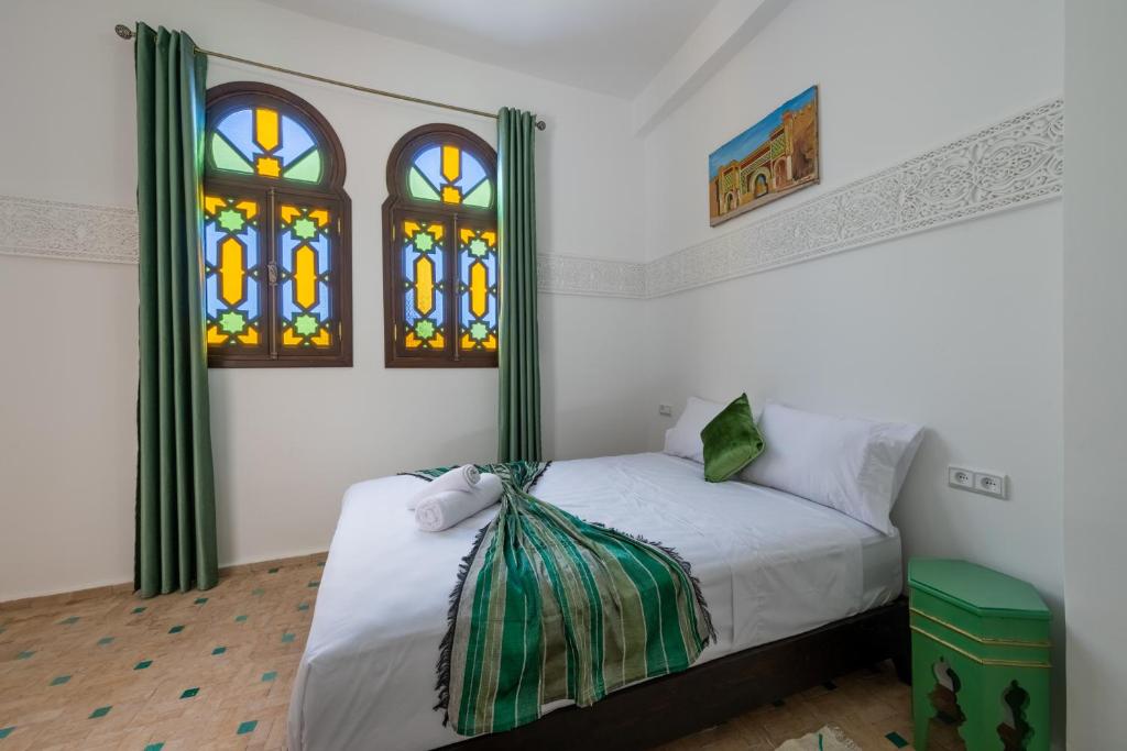 a bedroom with a bed and two stained glass windows at Riad SULTANA in Tangier