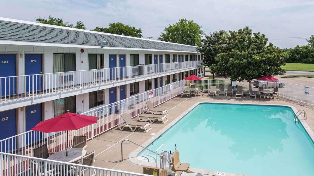 une piscine avec des tables et des parasols en face d'un hôtel dans l'établissement Motel 6-Goodlettsville, TN - Nashville, à Goodlettsville