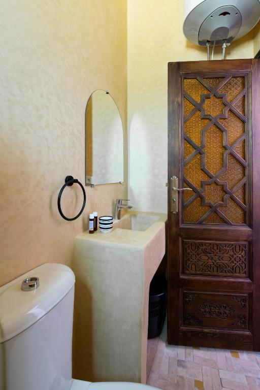 a bathroom with a toilet and a sink and a wooden door at Riad SULTANA in Tangier