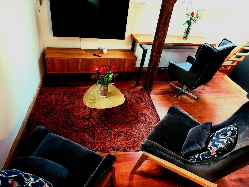 een woonkamer met stoelen en een tafel en een televisie bij Loft de la raquette in Bergen