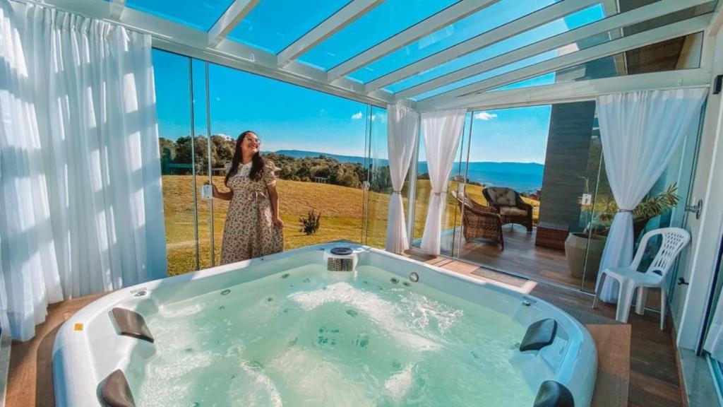 a woman standing in a bath tub in a room with a window at Casa Paraíso do Sol - Rancho Queimado - SC in Rancho Queimado