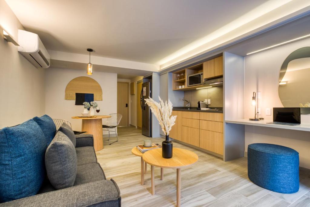 A wide view across an open-plan apartment with lounge seating, kitchenette and built-in dressing counter.
