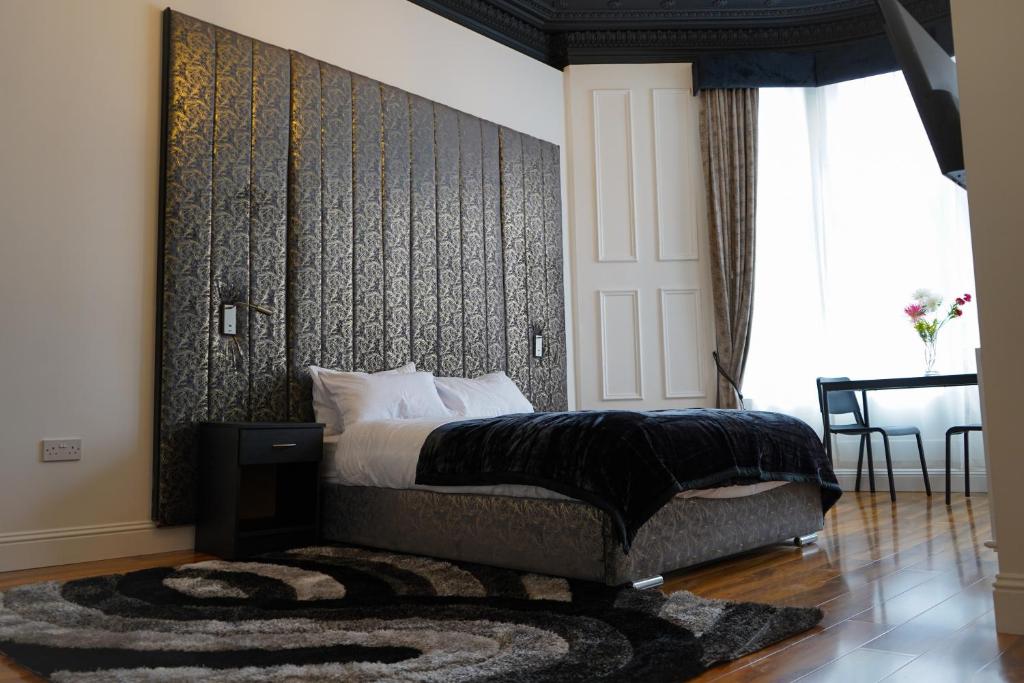 a bedroom with a bed with a black wall at S.H Apartments in Glasgow