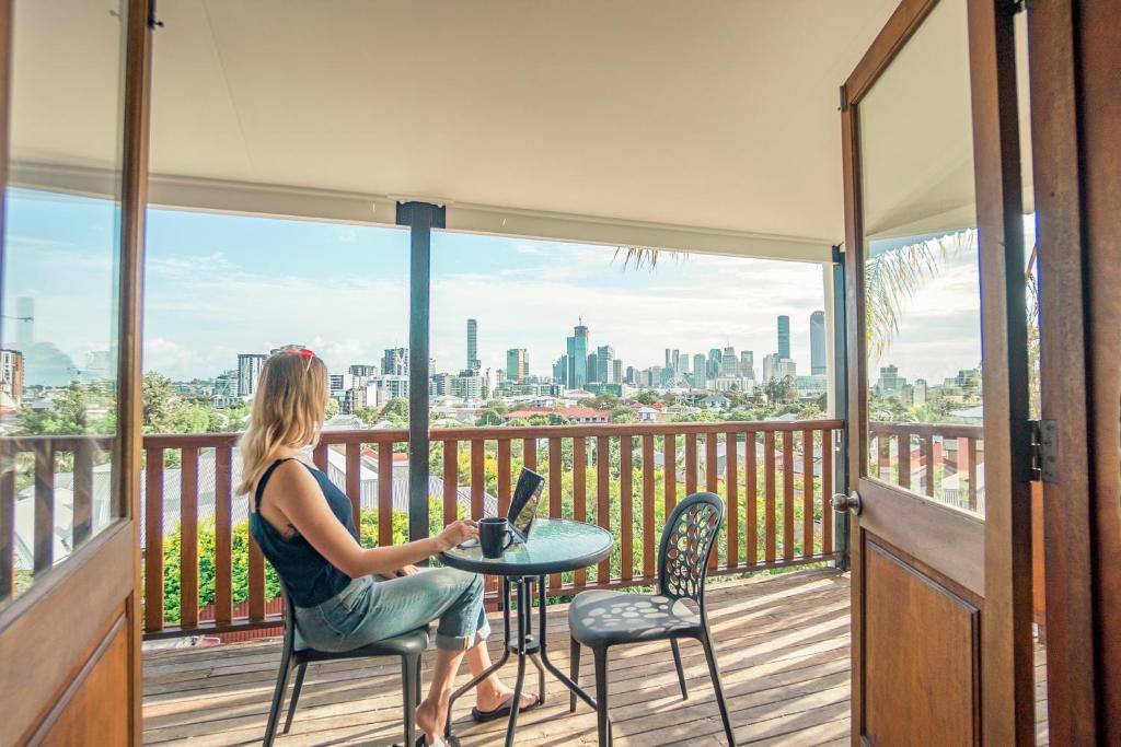 una mujer sentada en una mesa en un balcón con un ordenador portátil en Somewhere To Stay Backpackers, en Brisbane